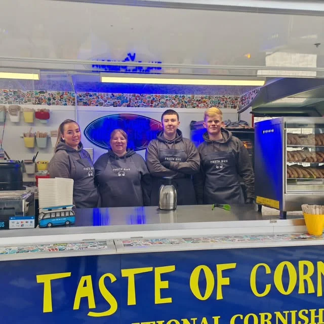 Four of the team behind the serving counter of the bus in Pasty Bus aprons.